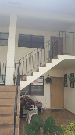 Front view of a building entrance with a staircase leading to an upper floor.