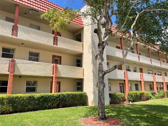 Front view of a multi-story building with balconies and red roof detailing.