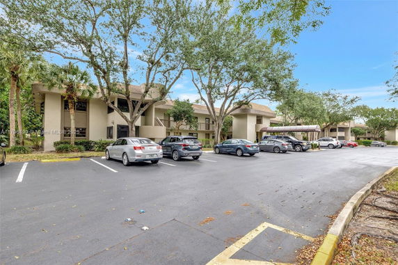 Parking area in front of a two-story building with multiple cars.