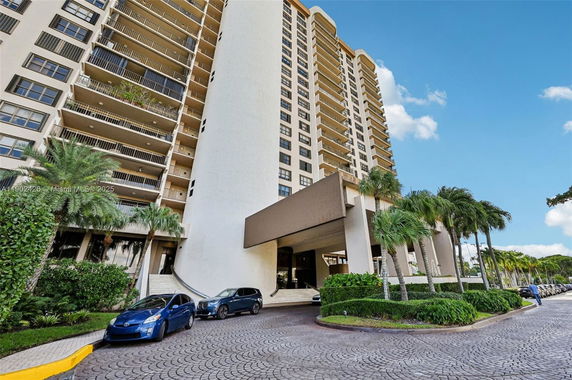 Front view of a high-rise building with balconies and a covered entrance.
