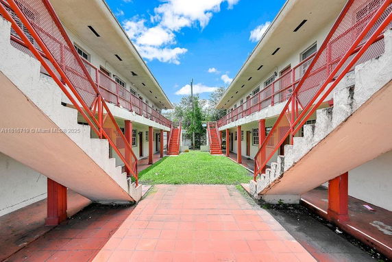 Front view of a two-story building with red staircases and railings on either side.