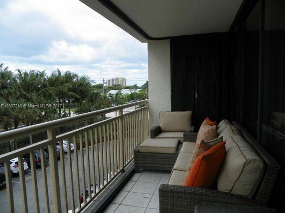 Balcony with outdoor seating offering a view of the surrounding buildings and trees.