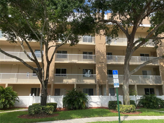 Front view of a multi-story residential building with balconies and a beige facade.