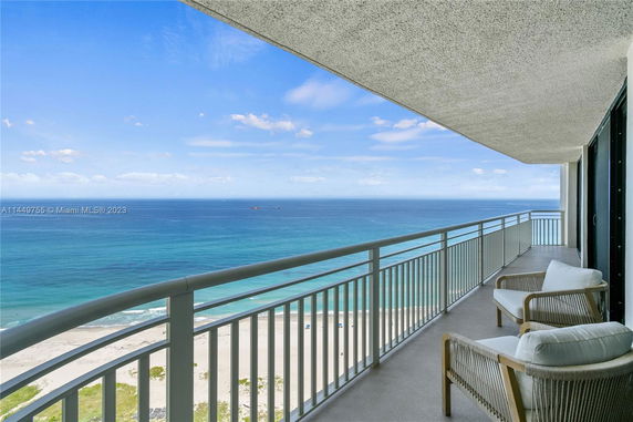 Panoramic view from a high-rise balcony overlooking the ocean and beach.