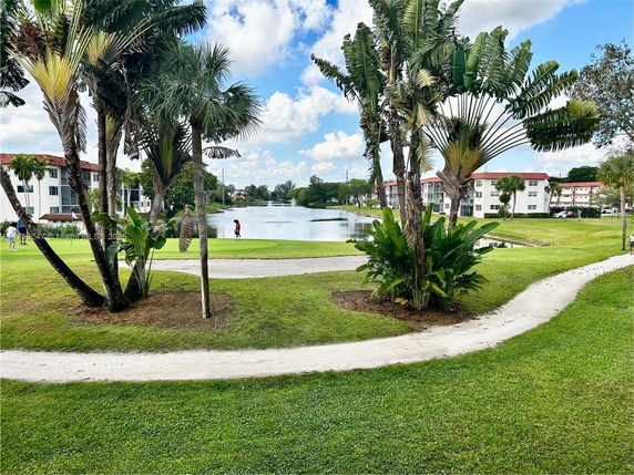 View of surrounding residential buildings and a lake with landscaped paths and trees.
