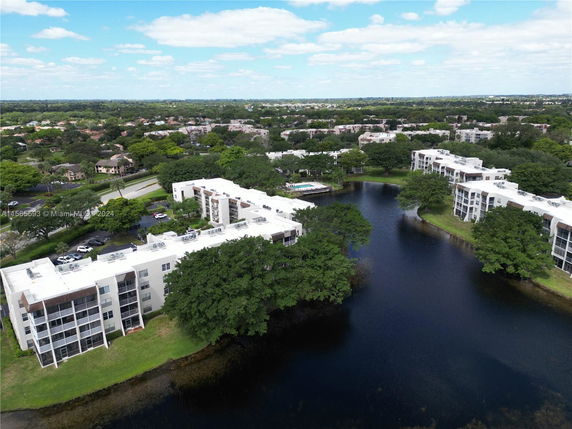 Aerial view of residential buildings surrounding a body of water with greenery.