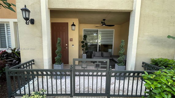 Front view of a house entrance with a small gated patio and decorative plants.