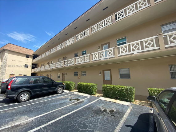 Outdoor parking space in front of a multi-story building with balconies.