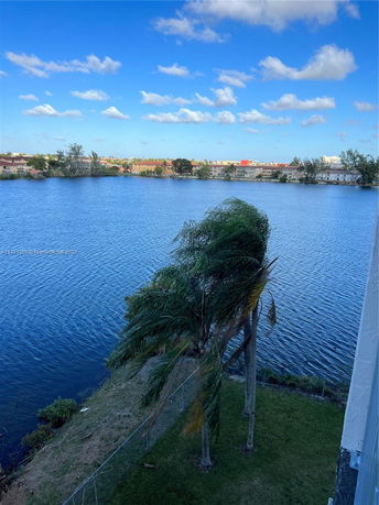 Panoramic view of a body of water surrounded by trees and distant buildings.