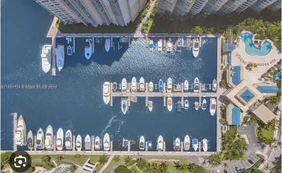 Aerial view of a marina with numerous boats docked and high-rise buildings nearby.