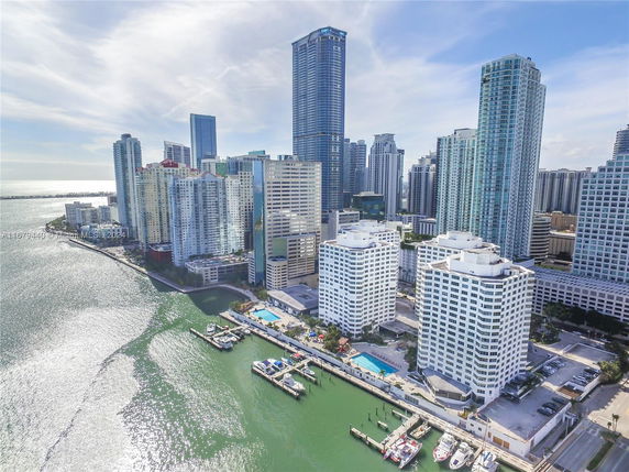 Aerial view of high-rise buildings near a waterfront with boats and marina.