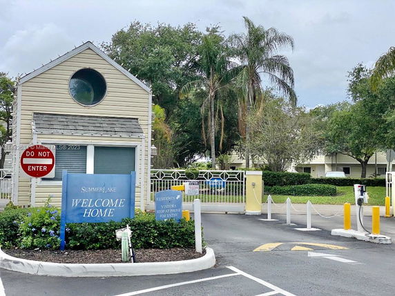 Entrance view of a residential building with gated access and a small guardhouse.