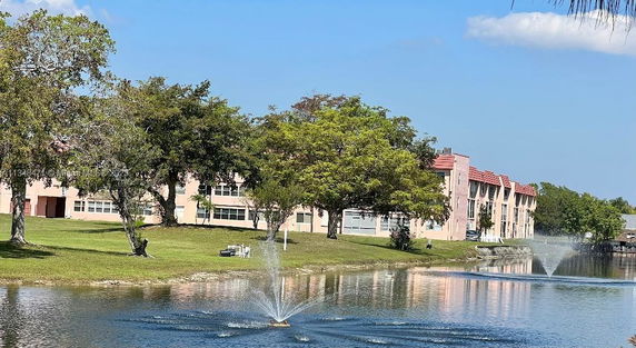 View of residential buildings with a pond and fountain in the foreground.