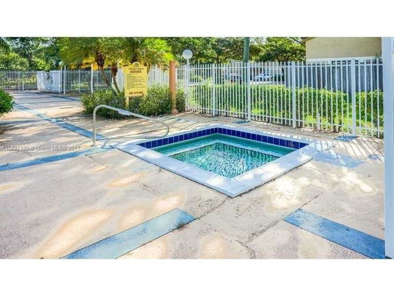 Outdoor swimming pool area with fencing and surrounding greenery.
