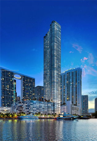 Front view of a tall modern skyscraper with glass facade by a waterfront.