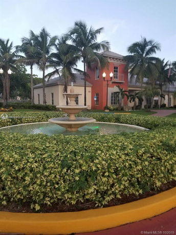 Front view of a building with a fountain and palm trees.