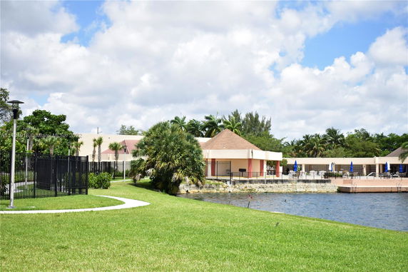 View of a building with surrounding grassy area and a body of water.