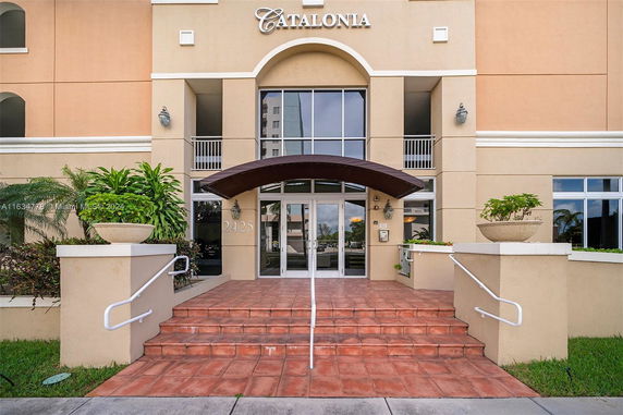 Front view of a building entrance with steps leading up to glass doors and a canopy.