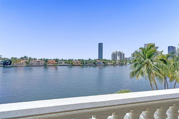 Panoramic view of a lake with buildings and palm trees in the distance.