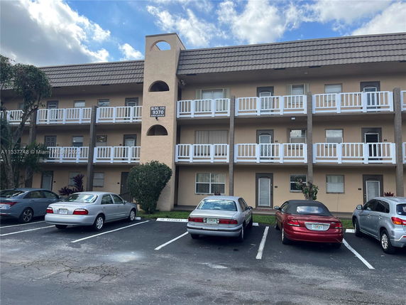 Front view of a multi-story residential building with a parking area.
