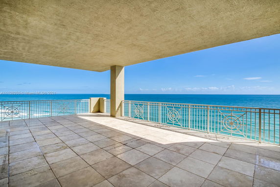 Balcony with tiled floor and ocean view, featuring ornate railing designs.