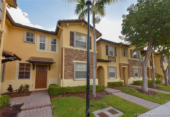 Front view of a two-story townhouse with brick accents and shutters.