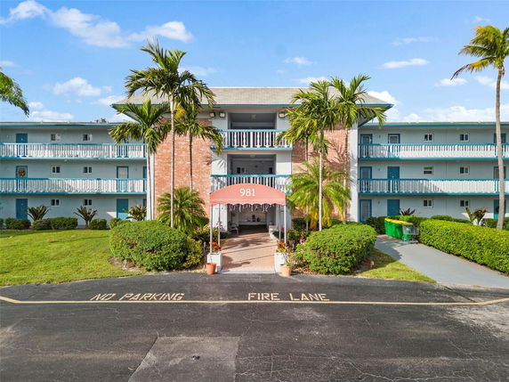 Front view of a three-story residential building with balconies and a brick facade entrance.