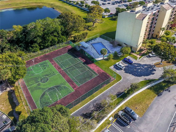 Aerial view of a sports area with basketball and tennis courts adjacent to a residential building.