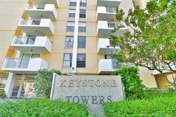 Front view of a multi-story building with balconies and a sign reading 'Keystone Towers'.