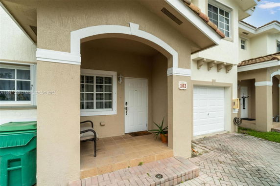 Front view of a two-story house with an arched entryway and attached garage.