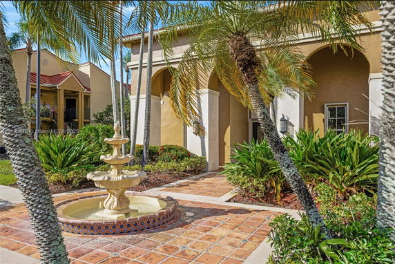Front view of a house with arched entrance and a decorative fountain in the foreground.