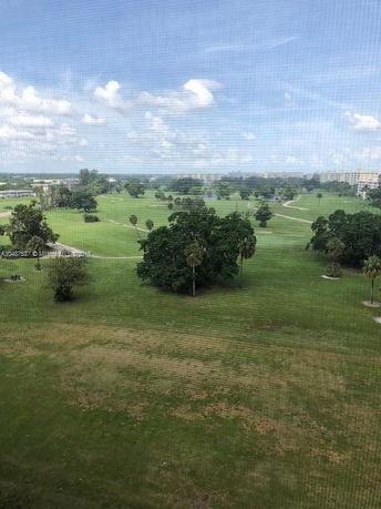 Panoramic view of a large grassy area with trees and distant buildings.