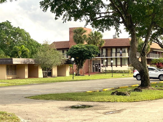 Front view of a two-story building with a tiled roof and large windows.