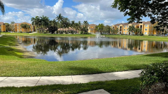Buildings surrounding a central pond with palm trees and a fountain.