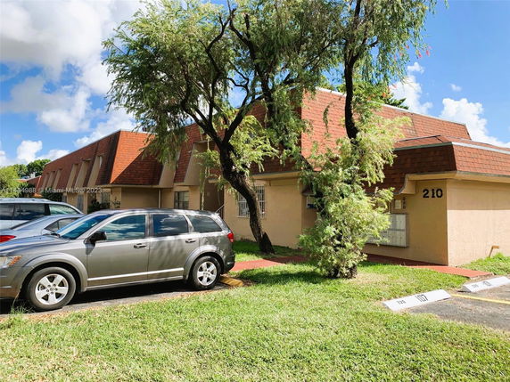 Front view of a building with a sloped roof and parking area.