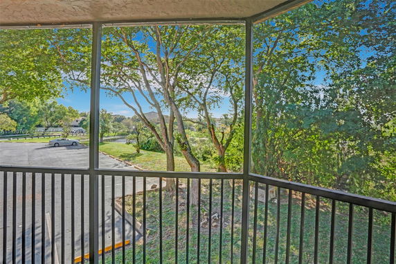 View from a balcony showing trees and a parking area.