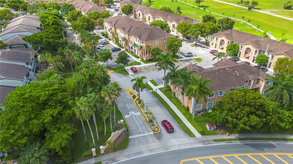 Aerial view of a residential apartment complex with surrounding greenery and roads.