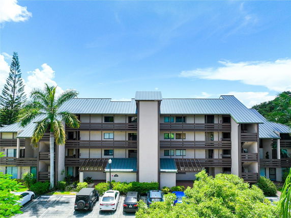 Front view of a multi-story building with a metal roof and balconies.