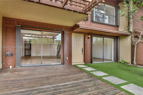 Front view of a two-story house with wooden deck and sliding glass doors.