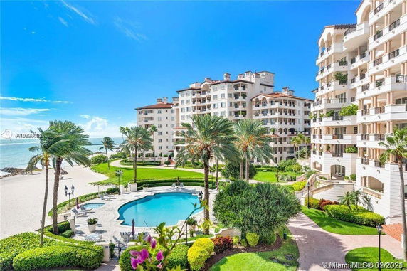 View of beachfront apartment buildings with a landscaped garden and pool area.