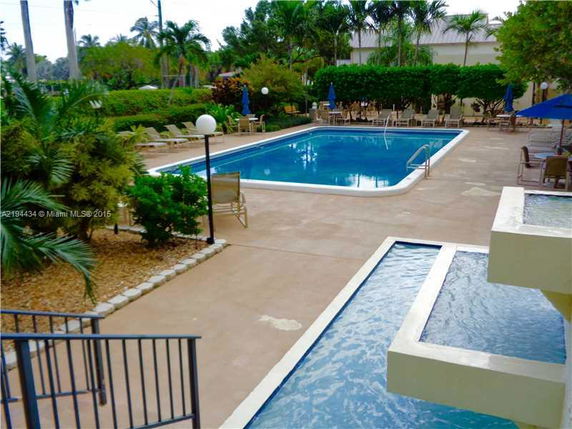 Outdoor view of a pool area with surrounding greenery and lounge chairs.