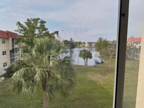 View of the surrounding area from a building window, showing a lake, trees, and nearby buildings.