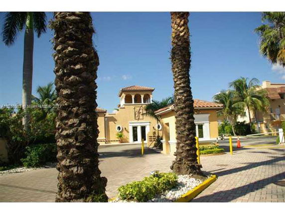 Front view of a building with a mediterranean architectural style and palm trees.