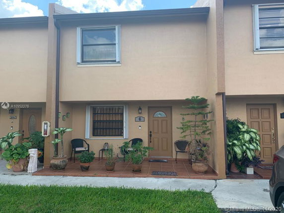 Front view of a two-story townhouse with a small patio and potted plants.