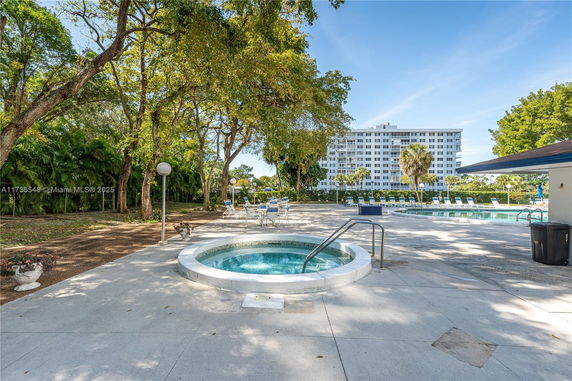 Outdoor swimming pool area with chairs and trees.