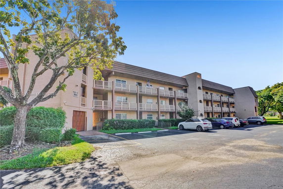 Front view of a multi-story residential building with balconies and parking area.