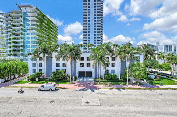 Front view of a multi-story building with prominent white facade and palm trees.