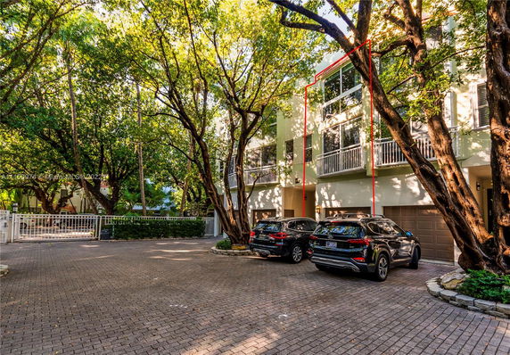 Outdoor parking area in front of a multi-story building with garages.