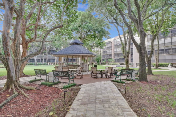 Gazebo and seating area surrounded by trees and apartment buildings.