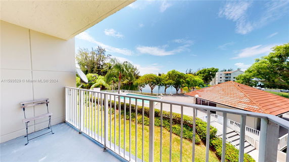 View from a balcony overlooking a landscaped area with trees and a distant water body.